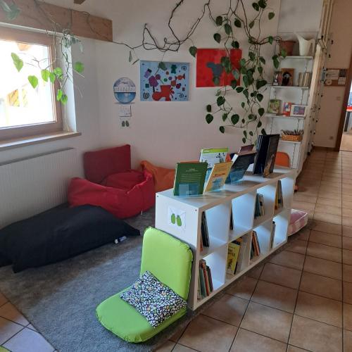 Man sieht die Lesewelt der VS Grinzens mit einem Regal, Sitzkissen und verschiedenen Büchern. 